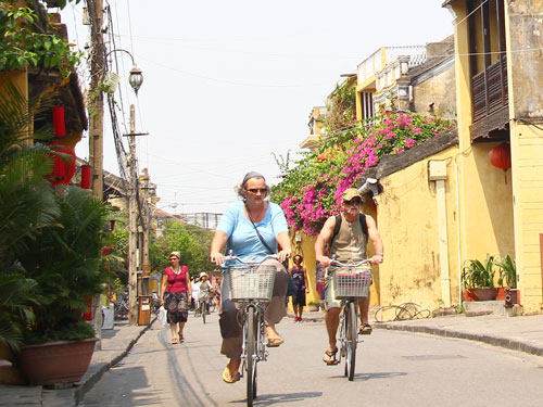 (Una escena familiar en el casco antiguo de Hoi An: paseo en bicicleta)